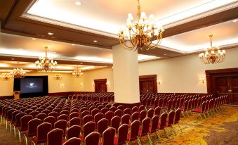 a large , empty conference room with rows of red chairs and chandeliers hanging from the ceiling at JW Marriott Hotel Caracas