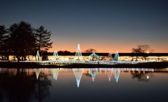 a serene night view of a waterfront area with lighted trees and buildings , reflecting in the calm water at Karuizawa Prince Hotel East
