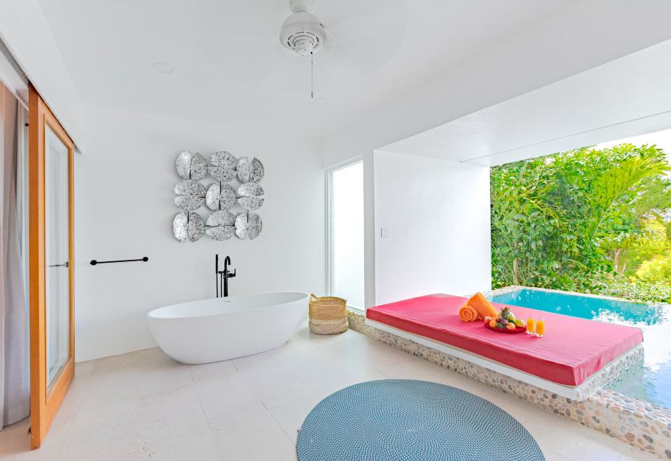 a modern bathroom with a white bathtub , a red bed , and a blue rug on the floor at Residences at Nonsuch Bay Antigua - Room Only - Self Catering