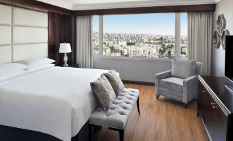 a hotel room with a large window overlooking the city , a bed , and a couch at Amman Marriott Hotel