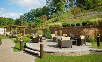 a beautiful backyard with a patio area surrounded by green grass and trees , creating a serene and inviting atmosphere at Courtyard Oneonta Cooperstown Area