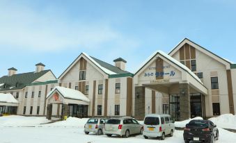 a snow - covered parking lot with several cars parked in front of a building , which is the hotel del sol in canada at Furano la Terre