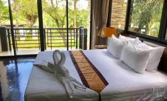 a hotel room with a king - sized bed , a window , and a view of the outdoors at Suwan Golf & Country Club