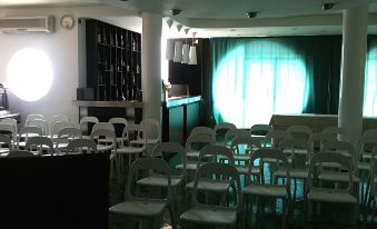 a room with chairs arranged in rows and a bar in the background , illuminated by a spotlight at Hotel la Lucertola