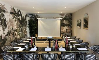 a conference room with a large table surrounded by chairs , and a projector screen on the wall at Les Manoirs des Portes de Deauville - Small Luxury Hotel of the World