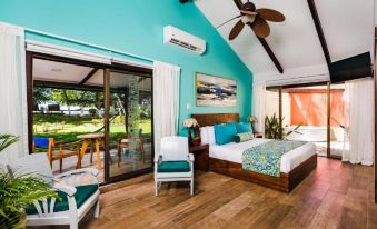 a spacious bedroom with a large bed , hardwood floors , and a sliding glass door leading to a patio at Bahia del Sol Beach Front Boutique Hotel