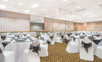 a large banquet hall with white chairs and tables set up for a formal event at Ramada by Wyndham Cumberland Downtown