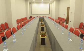 a long table with gray tablecloths and red chairs is set up in a large , empty room at Citrus Hotel