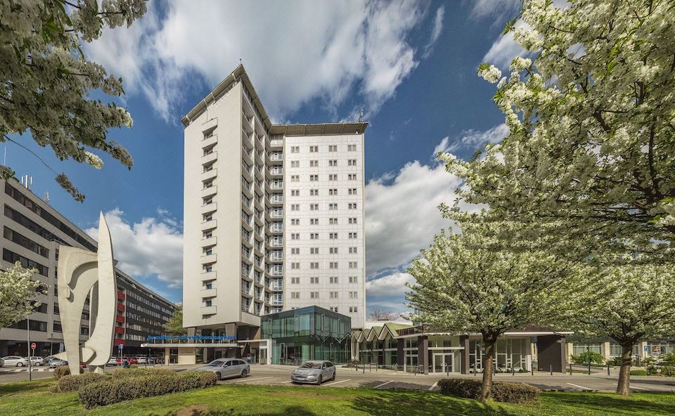 a tall white building with many windows is surrounded by trees and a parking lot at Hotel Continental