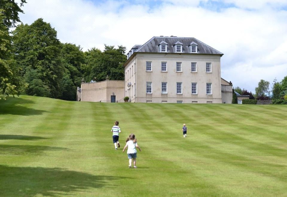 a group of children playing in a grassy field , with a large building in the background at Station House Hotel Letterkenny
