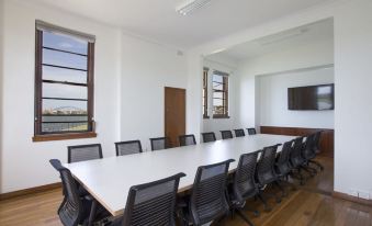 a large conference room with a long table and multiple chairs arranged for a meeting at Cockatoo Island Accommodation