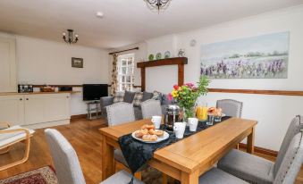 a dining table with chairs and a vase of flowers is set in a living room at Travelodge Scotch Corner Skeeby