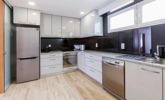 a clean and well - organized kitchen with stainless steel appliances , including a refrigerator , oven , and microwave at Central Suites