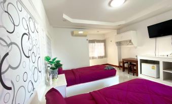 a modern bedroom with white walls , a flat - screen tv on the wall , and two beds with purple bedding at Sirasit 999 Mansion