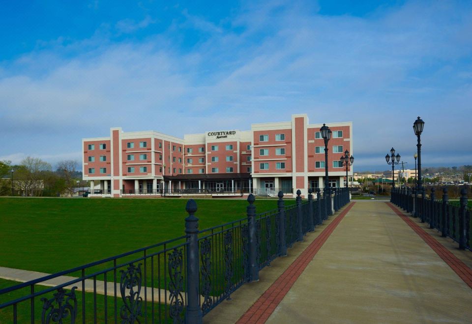 a brick building with a green lawn in front of it , and a walkway leading up to the entrance at Courtyard Rome Riverwalk