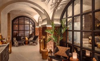 a modern , brick - and - glass building with a curved ceiling , surrounded by comfortable seating and plants at Vimmerby Stadshotell, WorldHotels Crafted