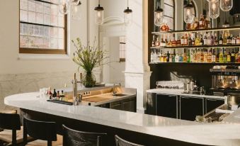 a modern bar with a curved counter and black chairs , featuring a variety of bottles behind the counter at August
