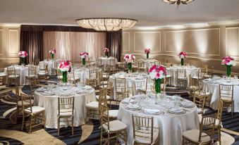 a large dining room with several round tables covered in white tablecloths , and several chairs arranged around them at Hilton Alexandria Mark Center