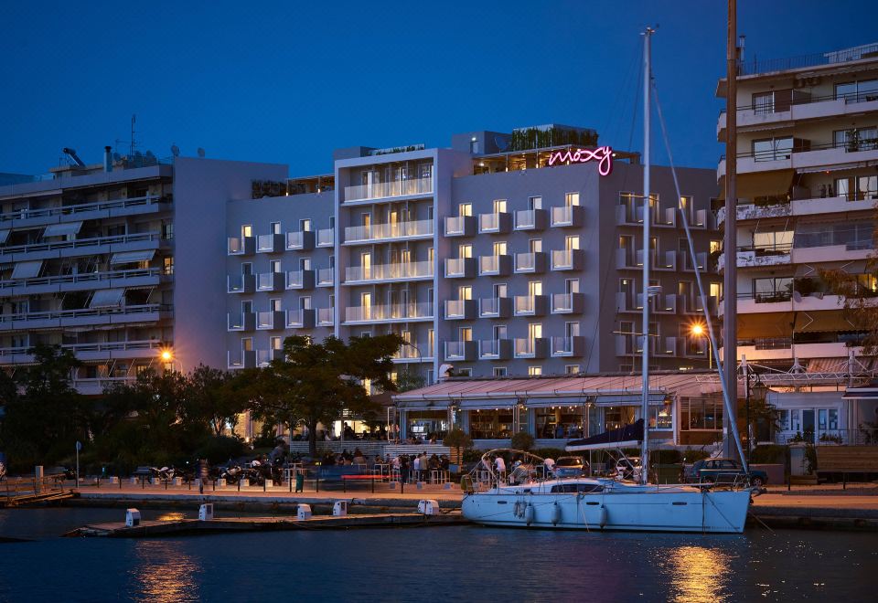 "a hotel building with the word "" ginger "" lit up on its facade , surrounded by boats in the water" at Moxy Patra Marina