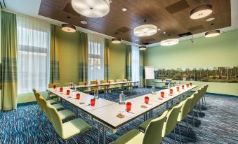 a conference room with a long table and chairs , surrounded by green walls and equipped with red plates and vases at Hey Lou Hotel Frankfurt Airport