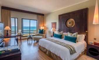 a luxurious hotel room with a large bed , wooden furniture , and a view of the ocean at Hotel Sea Cliff