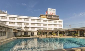 a large swimming pool is located in front of a hotel with a red sign at Hotel Fuji
