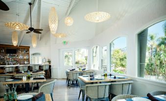 a restaurant with white walls , wooden tables and chairs , and large windows overlooking the outdoors at Catalina Canyon Inn