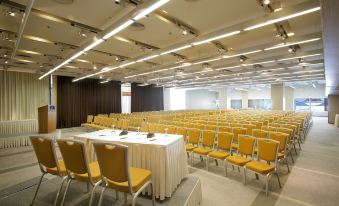 a large , empty conference room with rows of yellow chairs and tables set up for a meeting or event at Hotel Nikopolis