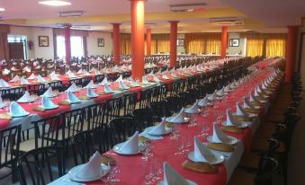 a large banquet hall filled with long tables , each table set with a white tablecloth and multiple place settings at Hotel Novo