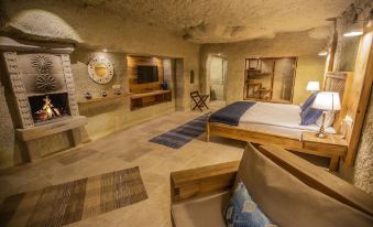 a cozy bedroom with a large bed , a flat - screen tv , and a bathroom in the background at Azure Cave Suites - Cappadocia