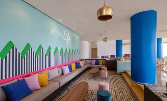 a modern lounge area with a blue wall , colorful couches , and a large wall mural featuring an arrow design at Allegro Agadir