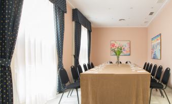 a long table with a brown cloth and several chairs is set up in a room with blue curtains at Hotel Inglaterra