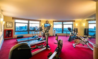 a well - equipped gym with various exercise equipment , including treadmills and weightlifting machines , situated in a spacious room with large windows at Cork International Hotel