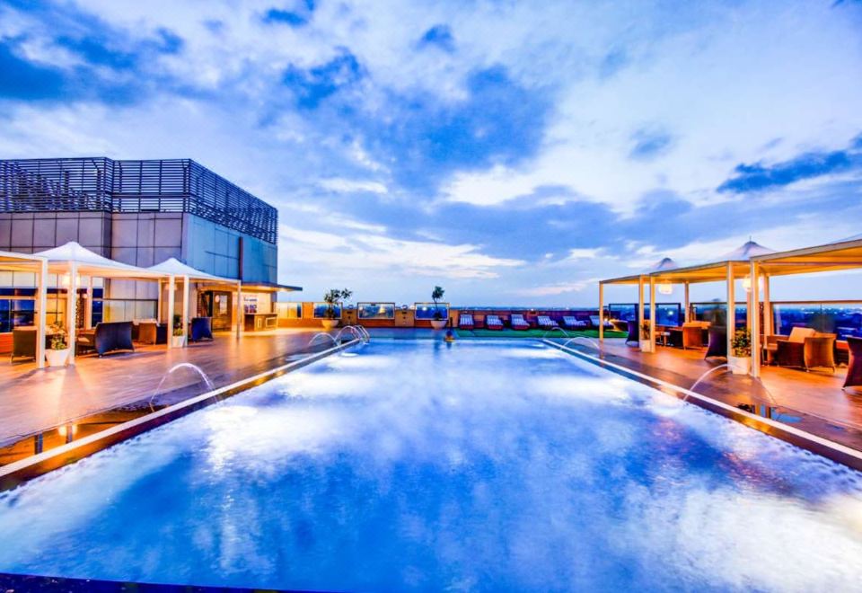a large , empty swimming pool is surrounded by lounge chairs and umbrellas on a rooftop at Radisson Blu Gorakhpur