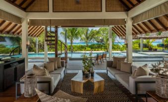 a living room with a couch , coffee table , and stairs leading to an outdoor pool area at Four Seasons Resort Maldives at Landaa Giraavaru