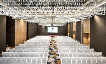 a large , empty conference room with rows of white chairs and chandeliers hanging from the ceiling at DoubleTree by Hilton Goa - Panaji