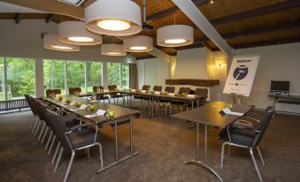 a conference room set up for a meeting , with tables and chairs arranged in rows at Fletcher Hotel Restaurant de Wipselberg-Veluwe