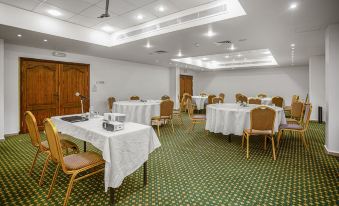 a large , well - lit conference room with multiple tables and chairs set up for a meeting or event at Grand Hotel Madaba