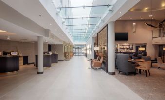 a spacious hotel lobby with a glass ceiling , large windows , and comfortable seating areas for guests at DoubleTree by Hilton London Heathrow Airport