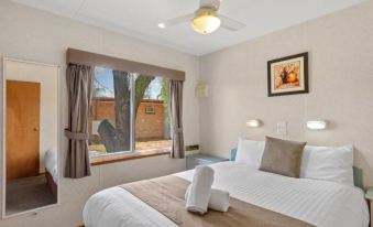 a bedroom with a large bed , white sheets , and a window looking out to a backyard at Discovery Parks - Port Augusta