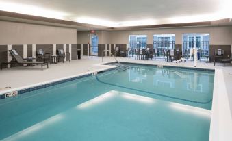 an indoor swimming pool with a blue tiled floor , surrounded by lounge chairs and umbrellas at Residence Inn Boston Westford