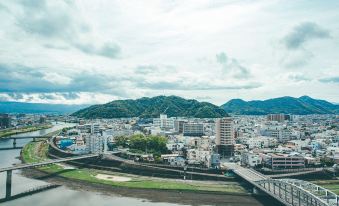 a cityscape with a river running through it , surrounded by buildings and mountains in the background at Numazu River Side Hotel