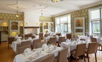 a large , well - lit dining room with multiple tables and chairs , ready for guests to sit and enjoy their meal at The Park Hotel