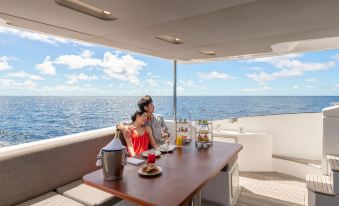 a man and a woman are sitting at a dining table on a boat , enjoying each other 's company at The St. Regis Maldives Vommuli Resort
