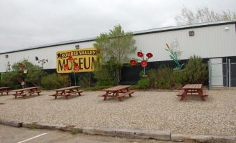 a parking lot with several picnic tables and benches , as well as a building in the background at Hotel Estevan