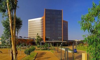 "a tall building with a glass facade is surrounded by a park and has the word "" bangkok "" on it" at Radisson Blu Hotel, Bamako