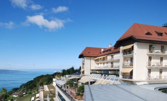 a large building with a red roof is perched on a hillside overlooking the ocean at Le Mirador Resort and Spa