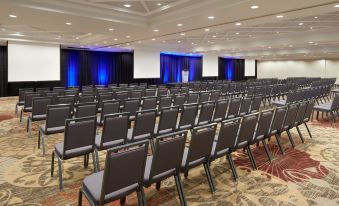 a large conference room filled with rows of black chairs and a stage at the front at Sheraton Parkway Toronto North Hotel & Suites