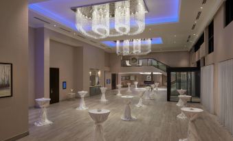 a large room with a spiral staircase and chandeliers , filled with numerous white candles on tables at Courtyard Oshawa