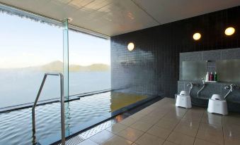 an indoor swimming pool with a view of the ocean , surrounded by a glass wall at The Lake View Toya Nonokaze Resort